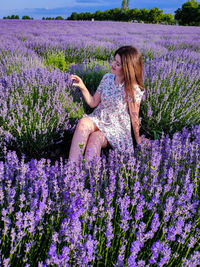 Woman sitting on purple flower in field