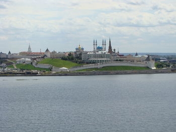 View of buildings by river against cloudy sky