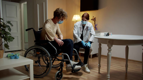 Young nurse checking temperature of patient at home