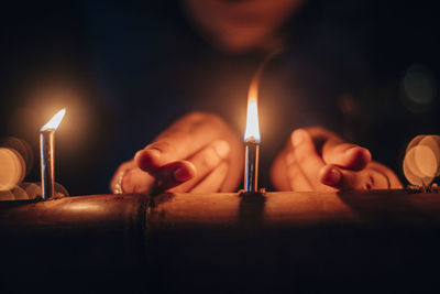 Close-up of hand holding lit candles