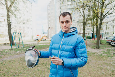 Portrait of man holding camera while standing outdoors