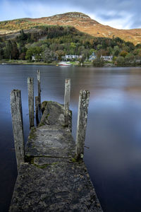 Wooden posts in lake against sky