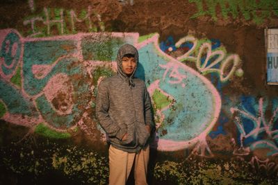 Full length of man standing against graffiti wall