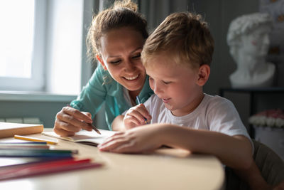 Cheerful woman drawing with boy