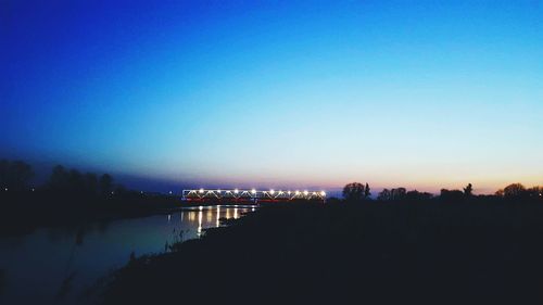 Scenic view of illuminated city against clear blue sky