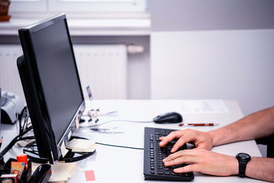 Cropped hands of business person using computer on desk