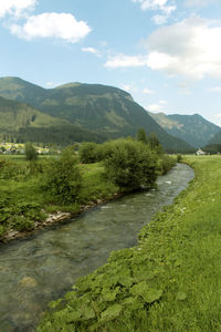 Scenic view of river by mountains against sky