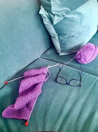 High angle view of crochet with wool and eyeglasses on sofa