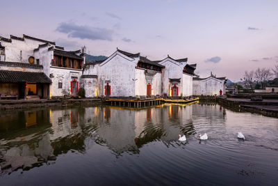 Lake and houses against sky in city