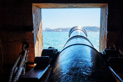 View out of a gunport in hull of the ship on the gun deck over the gun cannon muzzle in