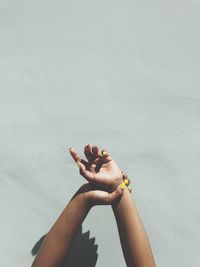 Cropped image of woman stretching arms against wall