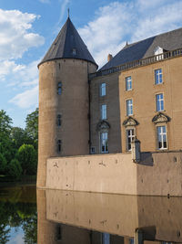 Low angle view of building by river against sky