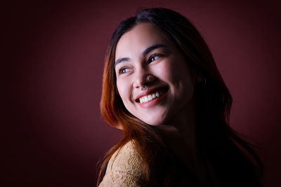 Portrait of young woman against black background