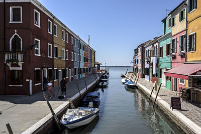 Boats moored in canal amidst buildings against sky