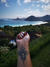 Cropped hand with tattoo against beach