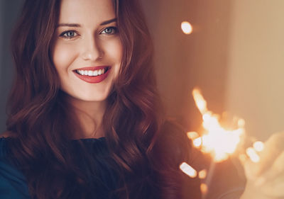 Portrait of young woman holding sparkler at night