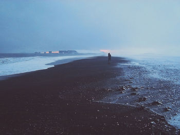 Person standing on beach against sky