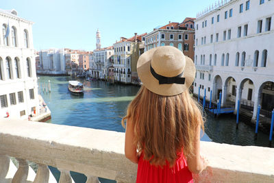 Rear view of woman standing by canal in city