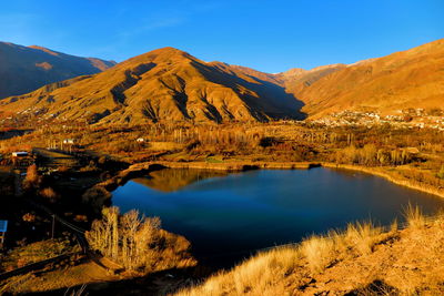 Scenic view of lake and mountains against blue sky