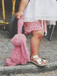 Low section of woman standing on pink shoes