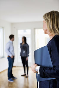 Mature real estate agent looking at couple discussing at home