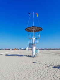 Lifeguard hut on beach against clear blue sky