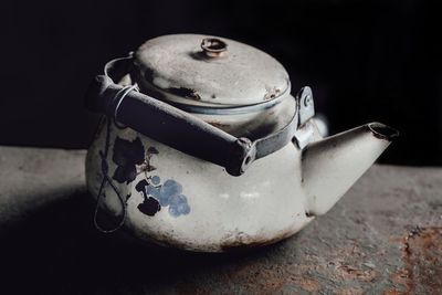 Close-up of teapot on table against black background