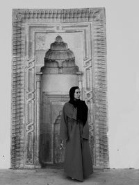 Woman standing on cross against building