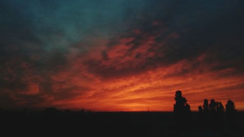 Silhouette people standing on land against sky during sunset