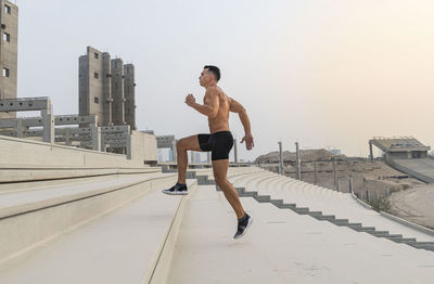 Full length of shirtless man in city against sky