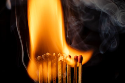 Close-up of burning candle against black background