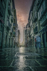 Wet street amidst buildings in city during rainy season