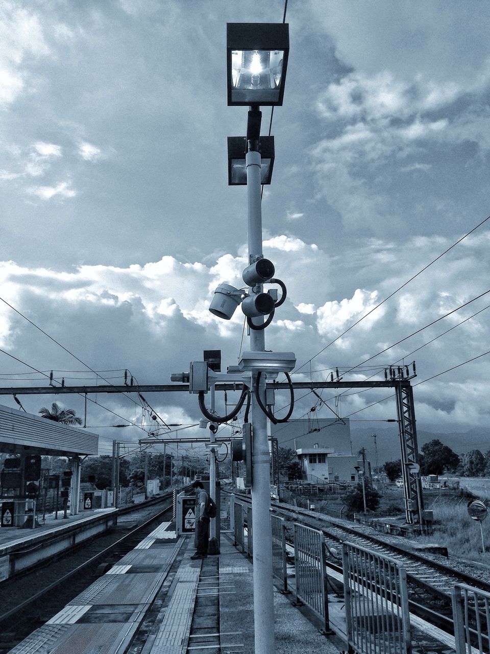 sky, transportation, cloud - sky, railroad track, rail transportation, built structure, street light, public transportation, railroad station platform, architecture, cloudy, railroad station, mode of transport, railing, cloud, the way forward, connection, lighting equipment, incidental people, travel