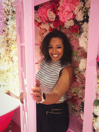 Portrait of smiling woman standing against floral decoration