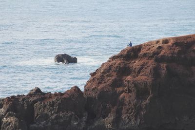 Scenic view of cliff by sea against sky