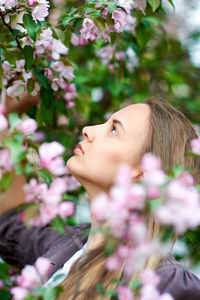 Close-up of woman with pink flowers against blurred background