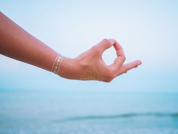 Cropped hand gesturing against sea