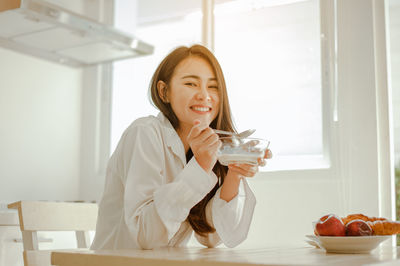 Smiling young woman holding ice cream on table