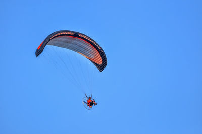 Low angle view of man paragliding against blue sky