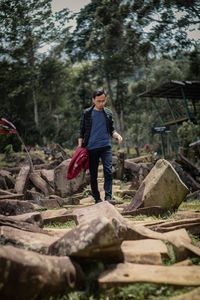 Full length of man standing on rock in forest