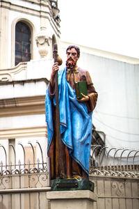 Low angle view of man standing by railing against building