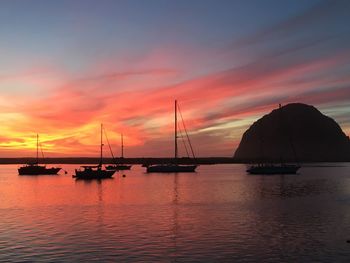 Silhouette sailboats in sea against sky during sunset