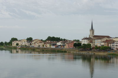 Buildings by lake against sky