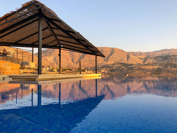 Reflection of swimming pool in lake against clear sky