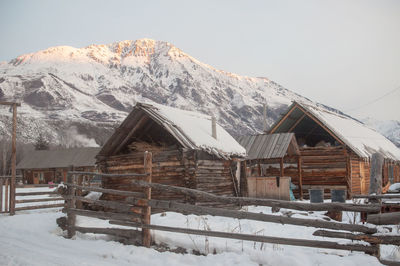 Snow covered landscape and houses against sky