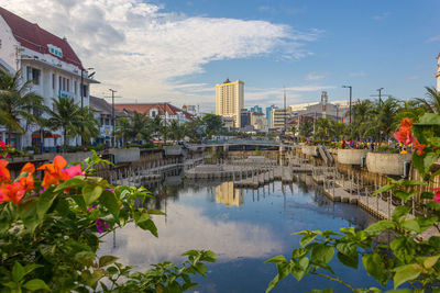 Buildings by river against sky