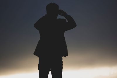 Rear view of silhouette man photographing against sky during sunset