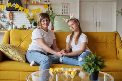 Friends using laptop while sitting on sofa at home