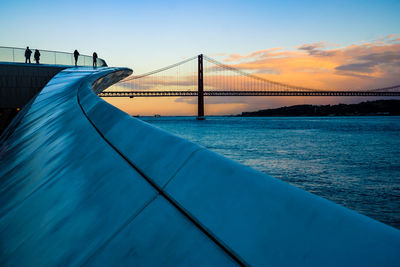 Bridge over sea against sky during sunset