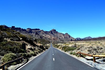 Road amidst mountains against clear blue sky